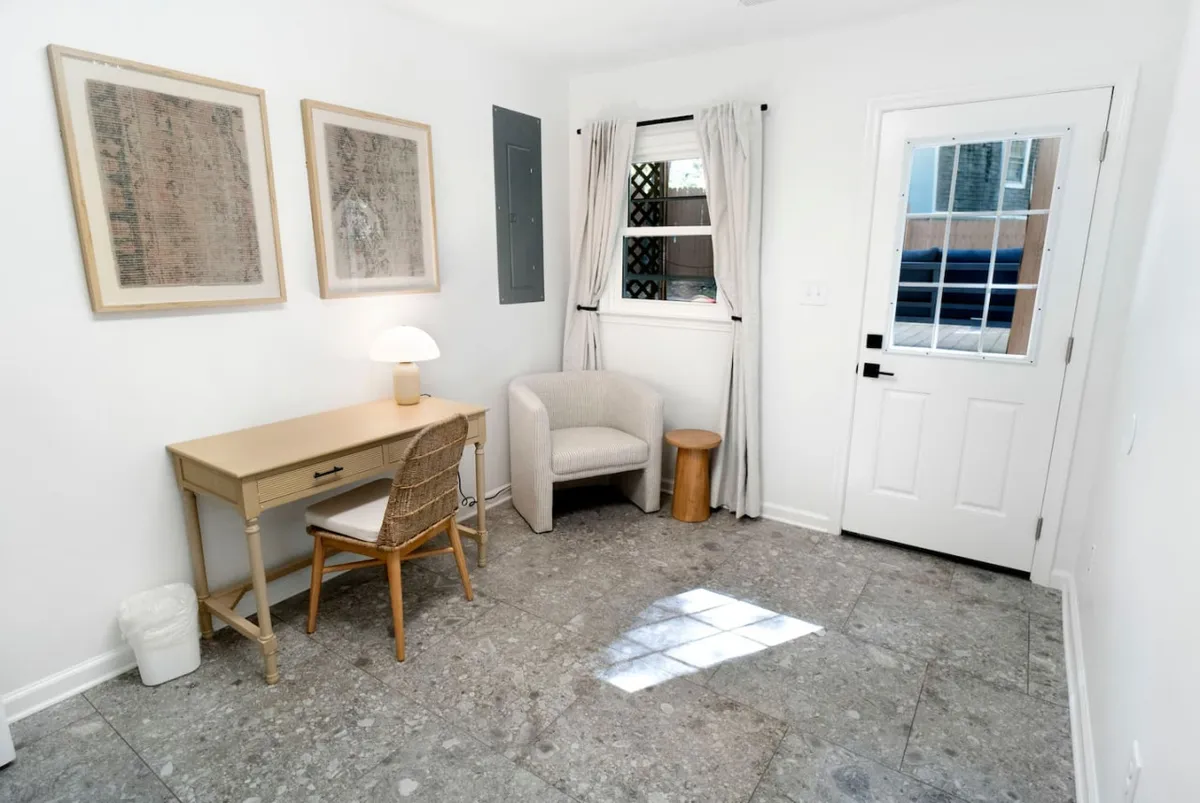 The photo features a tidy desk with a lamp and an armchair, accented by artwork on the walls. The setting exudes calm productivity, emphasizing a dedicated space for working, reading, or planning in peace.