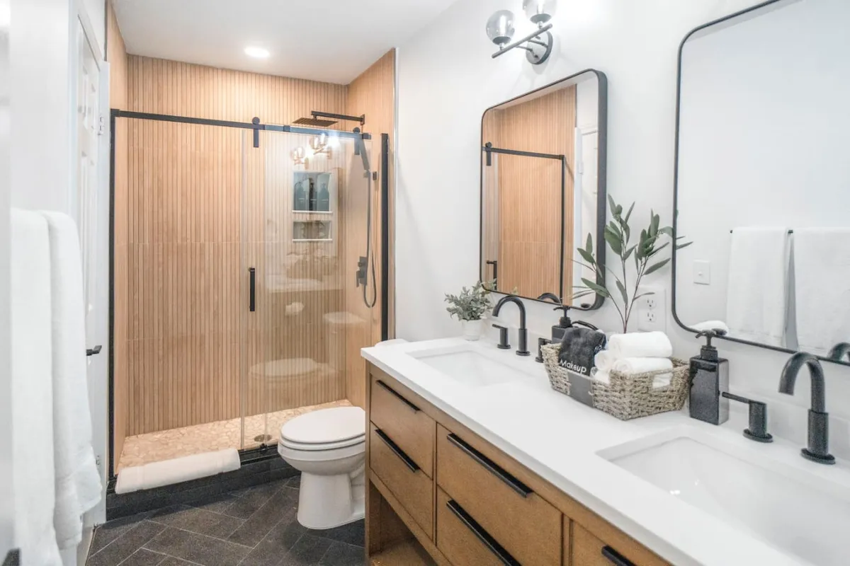 A modern ensuite bathroom with double vanity sinks, sleek mirrors, and a glass shower enclosure. The fresh, inviting atmosphere evokes a sense of personal luxury and self-care.