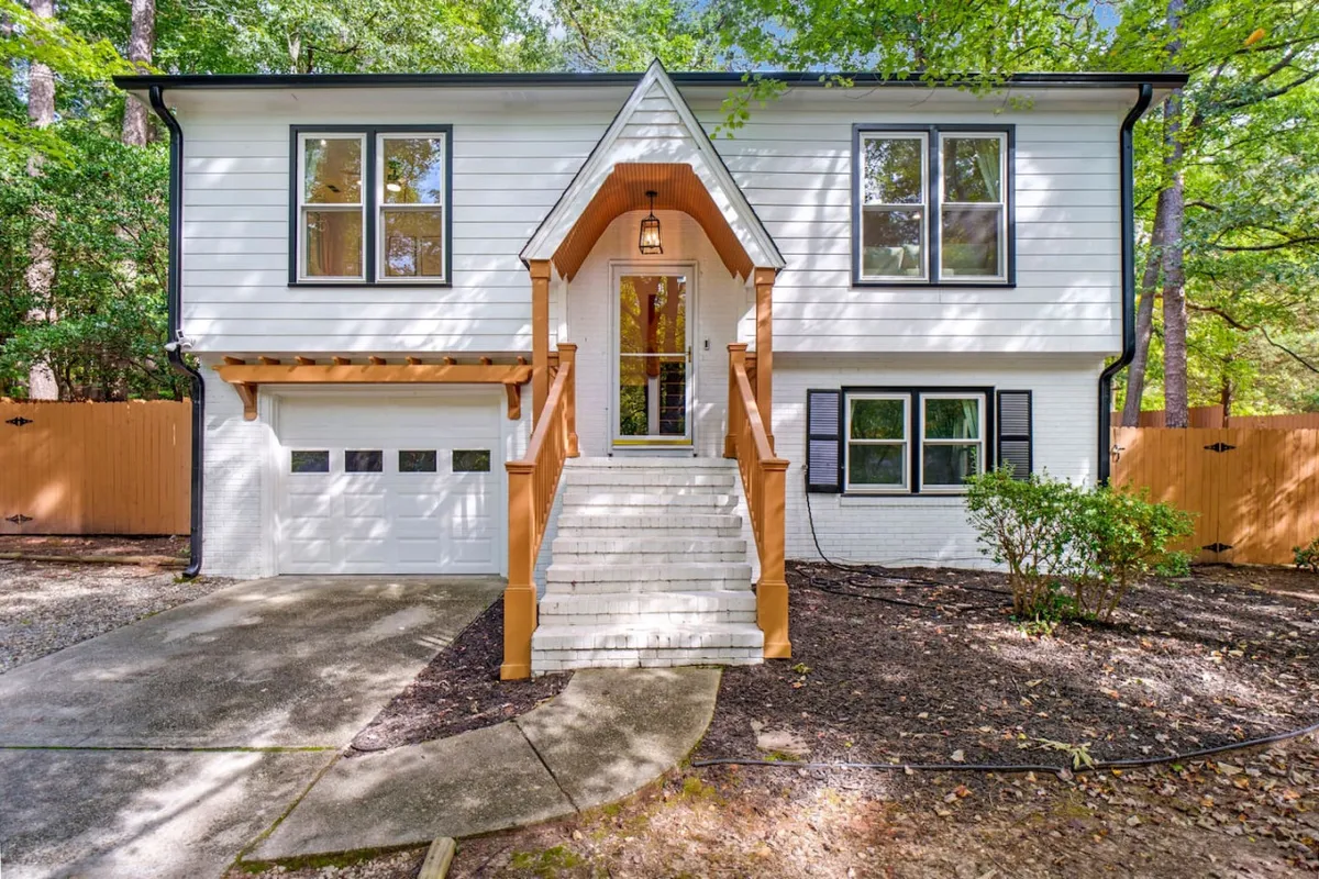 This exterior image features the front steps and entrance of Brandyapple Retreat, highlighted by large windows and a garage door. The inviting mood is underscored by warm lighting, suggesting a welcoming space to arrive and leave for daily activities.